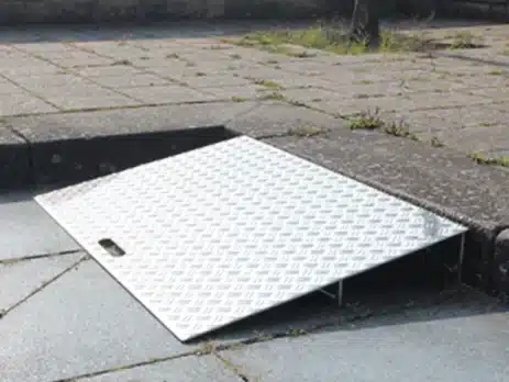Schräg angeordnete Aluminium-Rampe auf einem Bürgersteig, erleichtert den Zugang für Rollstuhlfahrer.