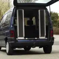 Öffnung des Kofferraums eines blauen Vans mit zwei vertikalen Rollstuhlschienen.