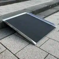 Stufenrampe aus Aluminium mit rutschfester Oberfläche, platziert auf einer Treppe aus Steinplatten.