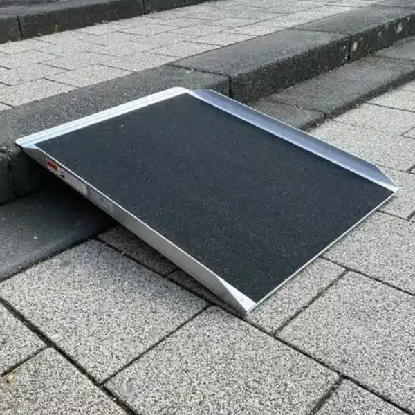 Stufenrampe aus Aluminium mit rutschfester Oberfläche, platziert auf einer Treppe aus Steinplatten.