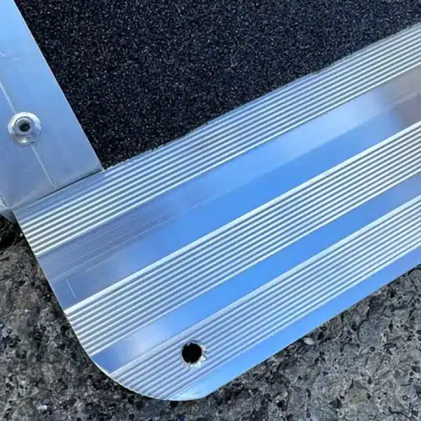 Aluminium-Rampe mit rutschfester Oberfläche und Erhebungen für besseren Halt, auf grauem Untergrund.
