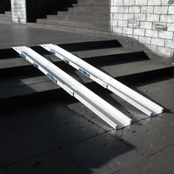 Rollstuhlrampe klappbar und teleskopierbar Ansicht diagonal Rampe aus Aluminium für den einfachen Zugang über Stufen, angeordnet auf einem Gehweg.