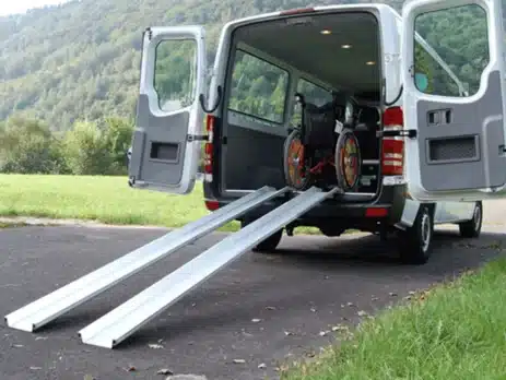 Fahrzeug mit offenen Türen und angelegten, klappbaren Rampen für Rollstuhlfahrer auf einer grünen Wiese.
