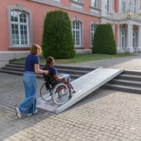 Eine Person im Rollstuhl benutzt eine Rollstuhlrampe im Freien