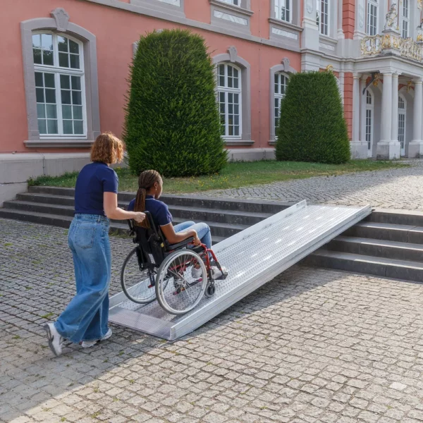 Eine Person im Rollstuhl benutzt eine Rollstuhlrampe im Freien