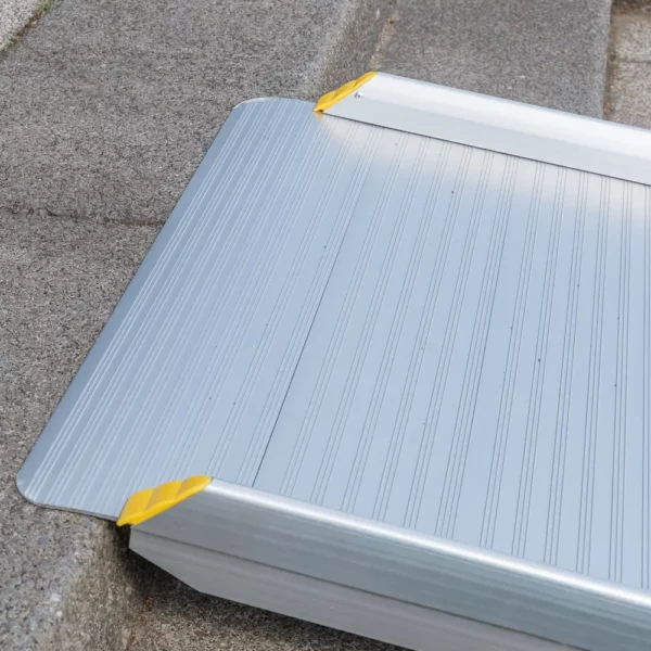Nahaufnahme des oberen Auflagewinkels einer tragbaren Aluminium-Rollstuhlrampe auf einer Betonstufen