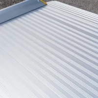 Nahaufnahme der rutschsicher geriffelten Fahrfläche einer Rollstuhlrampe aus Aluminium auf einer Betonfläche
