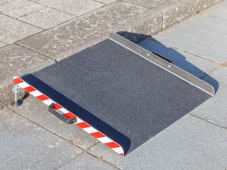 Eine tragbare Aluminium-Rollstuhlrampe mit rot-weiß gestreiften Rändern