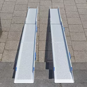 Zwei tragbare Rollstuhlrampen aus Aluminium mit Perforationen sind auf einer Treppe angebracht und überbrücken diese zur Straße.