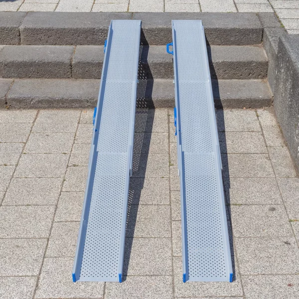 Zwei Rollstuhlampen Schienen für Rollstühle sind nebeneinander auf Steinstufen im Außenbereich angebracht und ermöglichen den Zugang für Rollstuhlfahrer über die Treppen.