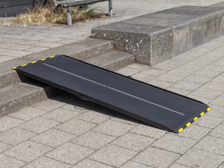 Eine schwarze Rollstuhlrampe aus Carbon mit gelben Rändern