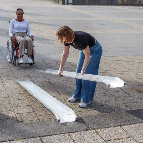 Eine Frau baut eine tragbare Rollstuhlrarmpe aus Aluminium auf