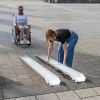 Eine Frau baut eine tragbare Rollstuhlrampe aus Aluminium auf