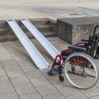 Ein roter Rollstuhl steht am unteren Ende von zwei Schienen einer Rollstuhlrampe