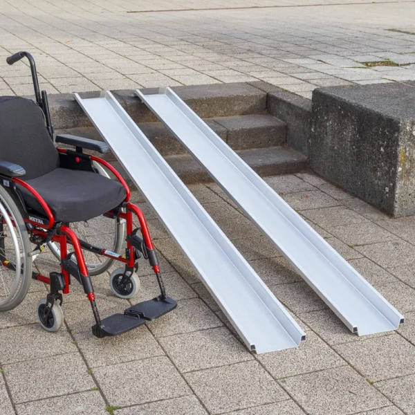 Ein roter Rollstuhl steht links neben zwei Schienen einer Rollstuhlrampe