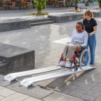 Eine Frau im roten Rollstuhl auf einer Schienenrampe aus Aluminium