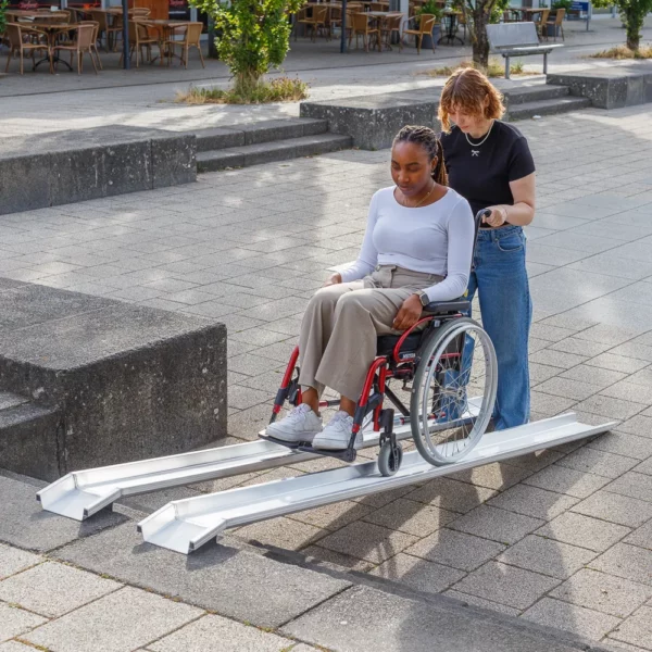 Eine Frau im roten Rollstuhl auf einer tragbaren Schienenrampe aus Aluminium