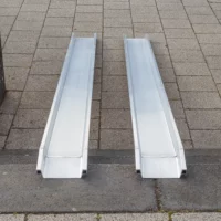 Zwei parallel platzierte tragbare Aluminiumschienen einer Rollstuhlrampe über Treppenstufen im Außenbereich von der oberen Stufe aus fotografiert.