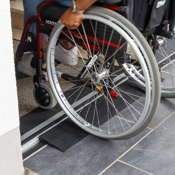 Eine Person im Rollstuhl benutzt zwei Schwellenkeile