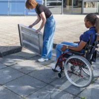 Eine Frau baut eine tragbare Rollstuhlrampe auf