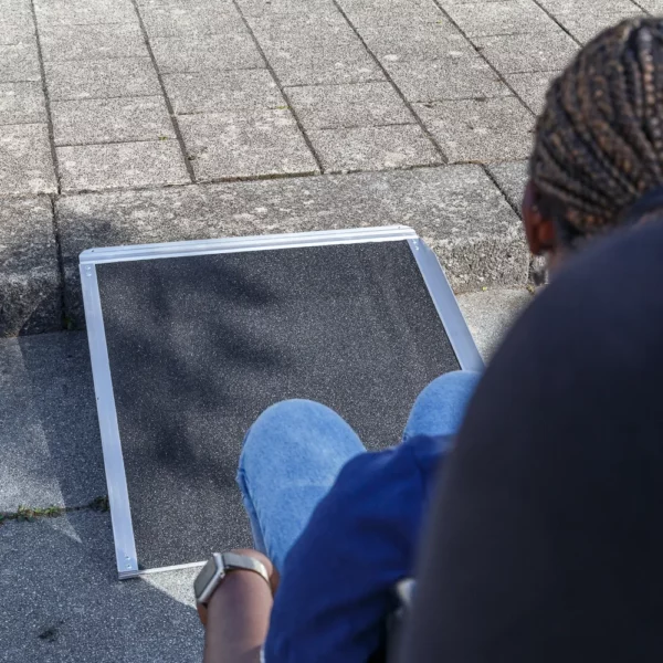 Eine Person im Rollstuhl nähert sich einer tragbaren Rampe