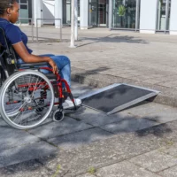 Eine Person im Rollstuhl nähert sich einer tragbaren Rampe