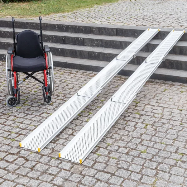 Ein Rollstuhl neben zwei tragbaren Rollstuhlrampen auf Kopfsteinpflaster